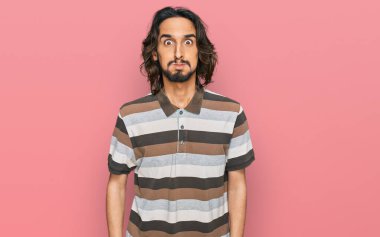 Günlük kıyafetler giyen genç İspanyol adam komik yüzlü yanakları şişiriyor. Havayla şişmiş ağız, çılgın bir ifade.. 