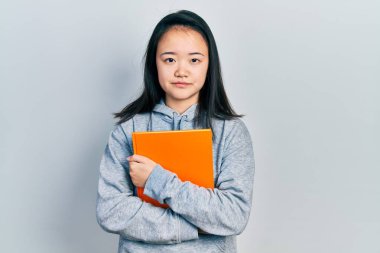 Genç Çinli kız elinde kitabı tutarken yüzünde ciddi bir ifade vardı. Basit ve doğal bir şekilde kameraya bakıyorsun.. 