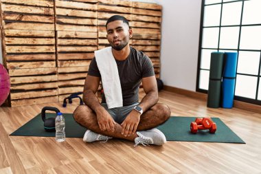 Spor salonundaki antrenman minderinde oturan genç Hintli adam dudaklarıyla balık suratı yapıyor, çılgınca ve komik bir jest. Komik ifade. 