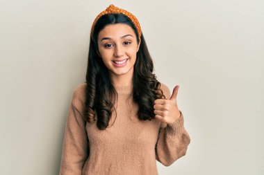 Gündelik kıyafetler giyen genç İspanyol kadın elleriyle mutlu bir jest yapıyor. Kameraya bakıp başarıyı gösteren ifade. 