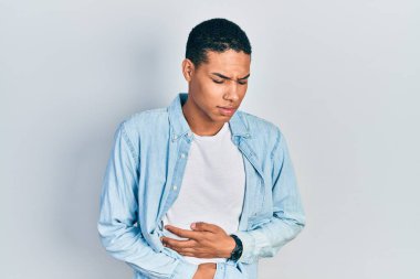 Genç Afro-Amerikalı adam, hazımsızlık, acı verici hastalıklar ve midesi üzerine gündelik giysiler giyiyor. Ağrı kavramı. 