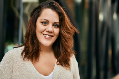 Genç İrlandalı artı cüsseli kız gülümseyerek şehirde mutlu mesut duruyor..