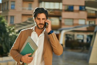 Genç İspanyol iş adamı ciddi bir ifadeyle şehirdeki akıllı telefondan konuşuyor..