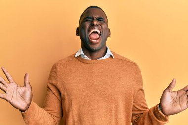 Sıradan kıyafetler giyen genç Afro-Amerikalı adam başarı için deli ve çılgınlığı kutluyor kollarını kaldırmış ve gözlerini kapatmış heyecanla bağırıyor. Kazanan konsept 