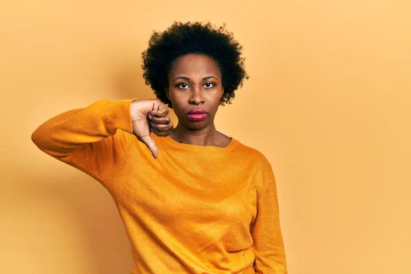 カジュアルな服を着ている若いアフリカ系アメリカ人女性は 親指を下にジェスチャーで拒絶と否定を示す不満と怒りを見ている 悪い表現 — ストック写真