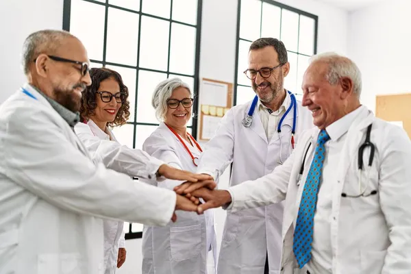 Grupa Lekarzy Średnim Wieku Uśmiechnięta Dłońmi Zjednoczonymi Spotkaniu Lekarskim Gabinecie — Zdjęcie stockowe