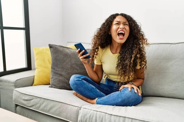 Mulher Hispânica Bonita Sentada Sofá Casa Usando Smartphone Irritado Louco — Fotografia de Stock