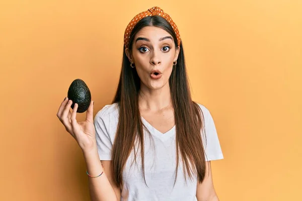 Beautiful Brunette Young Woman Holding Avocado Scared Amazed Open Mouth — Foto Stock