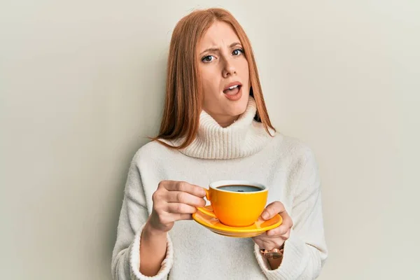 Молодая Ирландская Женщина Пьет Чашку Кофе Шокирующем Лице Выглядит Скептически — стоковое фото