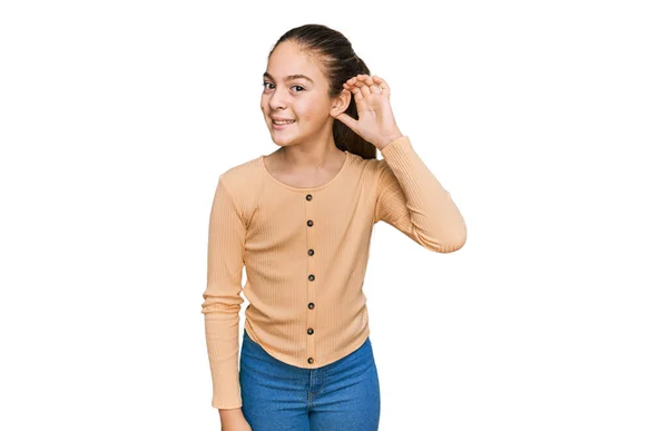 噂やゴシップに耳を傾ける耳の上に手で笑みを浮かべてカジュアルなセーターを着て美しいブルネットの女の子 聴覚障害の概念 — ストック写真