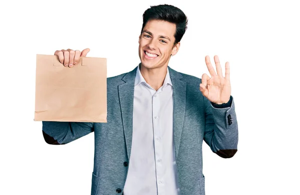 Young Hispanic Business Man Holding Paper Bag Bread Doing Sign — Fotografia de Stock