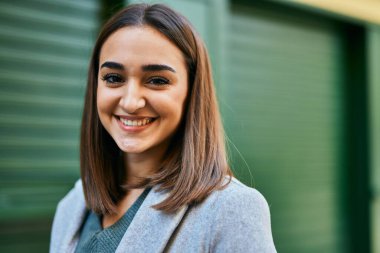 Genç İspanyol kız gülümseyerek şehirde mutlu mesut dikiliyor..