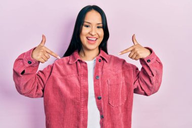 Güzel İspanyol kadın, burun piercingli, sıradan pembe ceketli, kendine güvenen, yüzünde gülümseme olan, kendini gururlu ve mutlu gösteren.. 