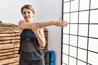 Orta yaşlı İspanyol kadın gülümsüyor spor merkezinde esniyor.