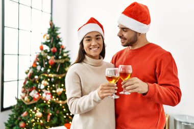 Genç İspanyol çift mutlu bir şekilde kadeh kaldırırken evde Noel ağacının yanında duruyor..