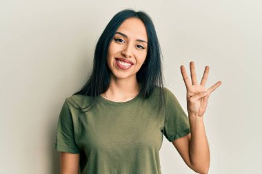 Gündelik tişört giyen genç İspanyol kız gülümseyerek kendinden emin ve mutlu bir şekilde dört numarayı gösteriyor ve işaret ediyor.. 
