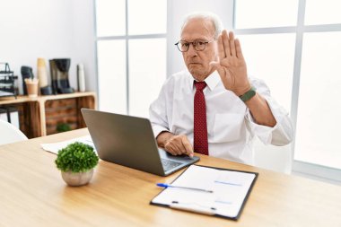 Ofiste bilgisayar kullanarak çalışan kıdemli bir adam avuç içiyle şarkı söylemeyi kesiyor. Yüzünde olumsuz ve ciddi bir jest olan uyarı ifadesi. 