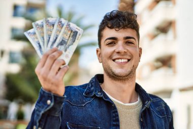 Genç İspanyol gülümseyen adam, şehirde Peru sol banknotlarını tutarken mutlu.