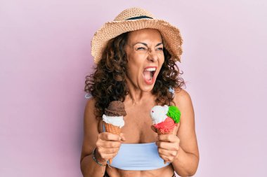 Orta yaşlı İspanyol bir kadın yaz tarzı giyinmiş elinde dondurmayla öfkeli ve öfkeli çığlıklar atıyor öfkeyle bağırıyor. öfke ve agresif konsept. 