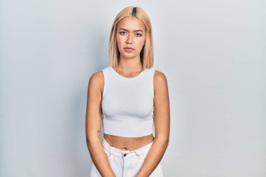 Kolsuz tişörtlü, sıradan giyinen güzel sarışın kadın. Yüzünde ciddi bir ifadeyle rahatlamış. Basit ve doğal bir şekilde kameraya bakıyorsun.. 