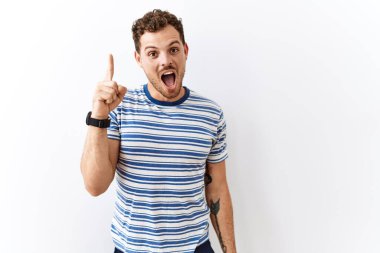 Tecrit edilmiş arka planda duran yakışıklı genç adam başarılı bir fikir işaret ediyor. Heyecanlı ve mutlu. Bir numara.. 