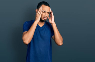 Genç Afro-Amerikalı bir adam stres yüzünden elleri başının üstünde gündelik tişört giyiyor. migren ağrısı. 