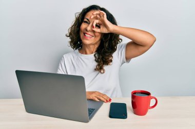 Ofiste çalışan orta yaşlı güzel bir kadın bilgisayarını kullanıyor. Gülümsüyor ve gülümsüyor. Tamam imzasını atıyor. 