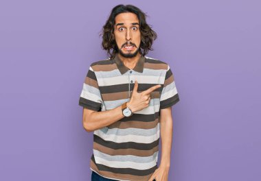 Gündelik kıyafetler giyen genç İspanyol adam endişeli ve gergin bir şekilde işaret ediyor. 