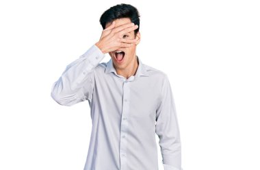 Genç İspanyol iş adamı iş kıyafetleri içinde şok içinde yüzünü ve gözlerini kapayarak utangaç bir ifadeyle parmaklarından bakıyor.. 