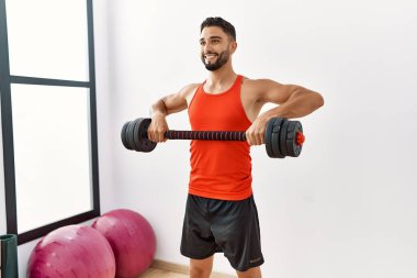 Genç Arap adam gülümsüyor spor merkezinde halterleri olan kendine güvenen bir antrenman.