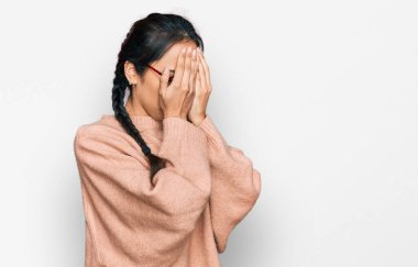 Gündelik kıyafetler giyen ve ağlarken yüzünü ellerle kapatan üzgün yüzlü gözlüklü genç İspanyol kız. depresyon kavramı. 