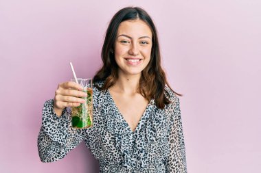 Genç esmer kadın mojito içiyor. pozitif ve mutlu görünüyor ve gülümsüyor kendine güvenen bir gülümsemeyle dişlerini gösteriyor. 
