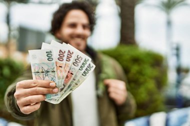 Yakışıklı İspanyol adam şehirde Czech Crown banknotları tutuyor.