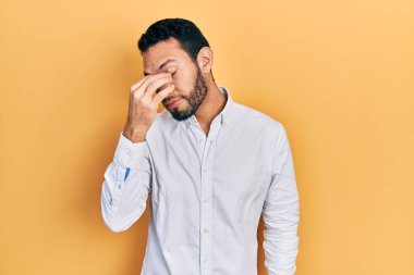 Sakallı, iş gömleği giyen, burnu ve gözleri ovuşturmaktan yorgun düşmüş, yorgun ve baş ağrısı çeken İspanyol bir adam. Stres ve hüsran kavramı. 