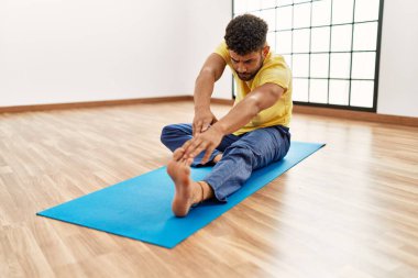 Genç Arap sporcu adam spor merkezinde esneme hareketlerine konsantre oluyor..