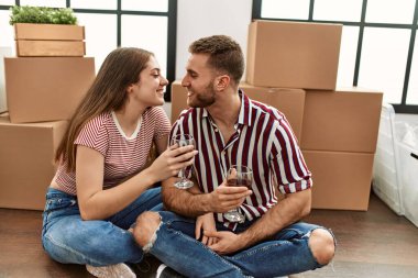 Yeni evimizde kırmızı şarapla kadeh kaldırırken gülümseyen beyaz bir çift.