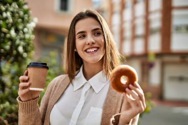 Genç İspanyol iş kadını gülümseyerek şehirde kahvaltı yapıyor..