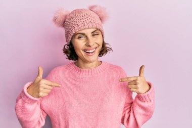 Genç esmer, sevimli yün şapkalı, kendine güvenen, yüzünde gülümseme olan, kendini gururlu ve mutlu gösteren bir kadın.. 