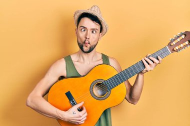 Latin kökenli genç bir adam klasik gitar çalıyor ağzıyla balık suratı yapıyor ve gözlerini kıstı, çılgın ve komik.. 