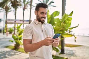 Sokakta akıllı telefon kullanan, kendine güvenen genç bir İspanyol.