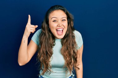 Gündelik kıyafetler giyen genç İspanyol kız başarılı bir fikri işaret ediyor. Heyecanlı ve mutlu. Bir numara.. 