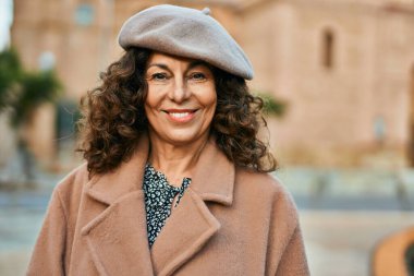 Orta yaşlı İspanyol kadın gülümseyerek şehirde mutlu mesut dikiliyor..