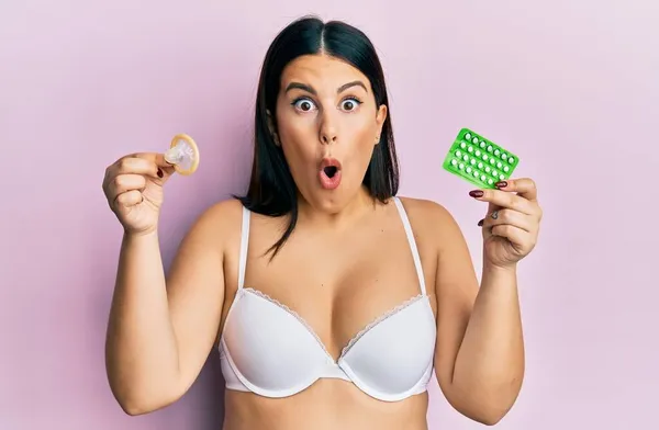 Elinde Prezervatif Doğum Kontrol Hapları Tutan Güzel Esmer Kadın Şaşkınlık — Stok fotoğraf