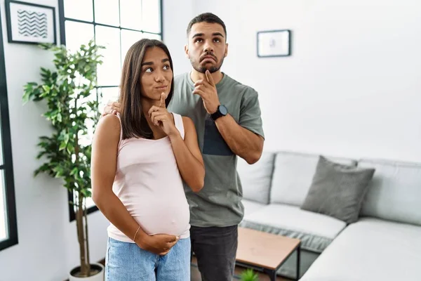 若い異人種間のカップル期待赤ちゃん 妊娠中の腹の思考に触れます集中しています疑いについて指で顎と疑問に思って検索 — ストック写真