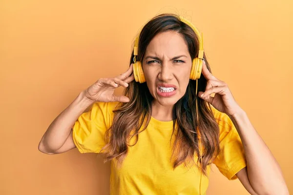 ヘッドフォンを使用して音楽を聴いている若いラテン語の女性は混乱しない表現 疑わしい概念 — ストック写真