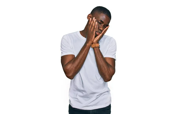 若いアフリカ系アメリカ人の男性は カジュアルな白いTシャツを着て疲れて手を顔 うつ病や悲しみ 動揺や問題のためにイライラカバー — ストック写真