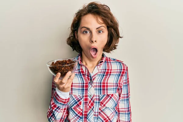 Junge Brünette Frau Hält Schale Mit Rosinen Der Hand Erschrocken — Stockfoto