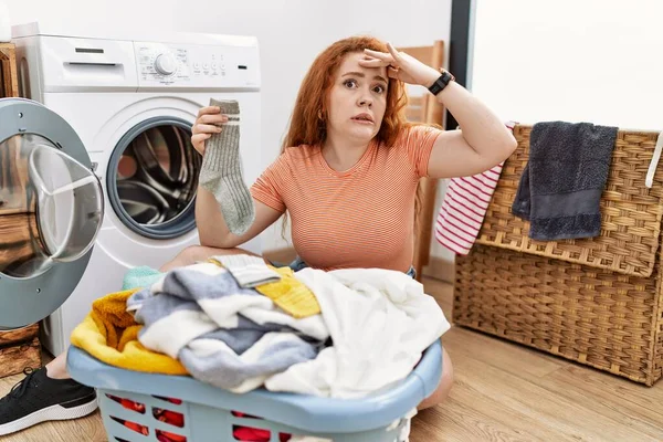 若い赤毛の女性は洗濯機に汚れた洗濯機を入れて心配し 額に手で問題について強調しました 危機への神経と不安 — ストック写真