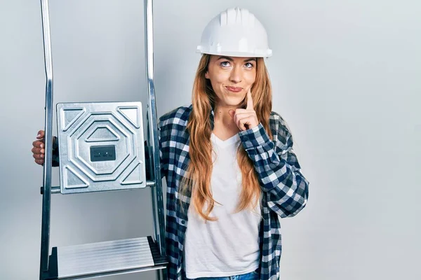 Mulher Caucasiana Jovem Vestindo Hardhat Segurando Escada Rosto Sério Pensando — Fotografia de Stock