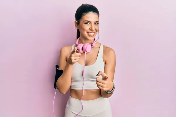 Young Hispanic Woman Wearing Gym Clothes Using Headphones Pointing Fingers — Stock Photo, Image